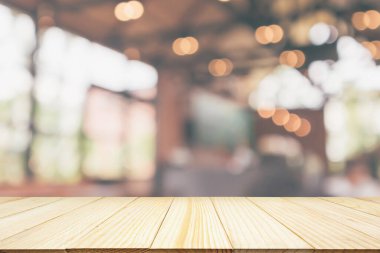 Kafe restoranı ya da kahve dükkanı penceresi olan boş ahşap masa üstü ya da montaj ürün gösterimi için bokeh ışığı arka planına odaklanmış soyut bulanıklık.