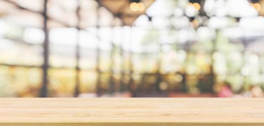 Kafe restoranı ya da kahve dükkanı penceresi olan boş ahşap masa üstü ya da montaj ürün gösterimi için bokeh ışığı arka planına odaklanmış soyut bulanıklık.