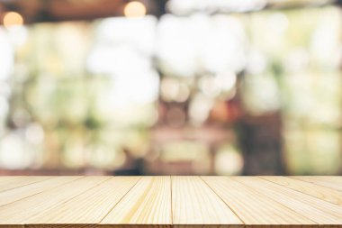 Kafe restoranı ya da kahve dükkanı penceresi olan boş ahşap masa üstü ya da montaj ürün gösterimi için bokeh ışığı arka planına odaklanmış soyut bulanıklık.