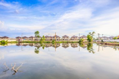 Yeni ev binası yansıması gölde suyla birlikte bulutlu ve mavi gökyüzü olan konut inşaat sahasında.