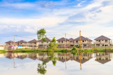 Yeni ev binası yansıması gölde suyla birlikte bulutlu ve mavi gökyüzü olan konut inşaat sahasında.