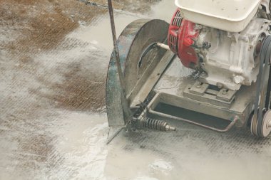 İnşaat alanında beton yol kesen elmas testeresi kullanan bir işçi.