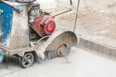 İnşaat alanında beton yol kesen elmas testeresi kullanan bir işçi.