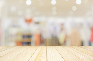Çağdaş giyim mağazası iç mekan bulanıklığı olan boş ahşap masa üstü. Ürün gösterimi için bokeh ışığı ile soyutlanmış arkaplan.