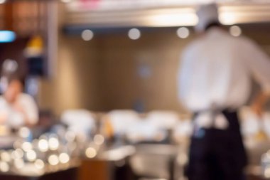 Aşçı, restoran mutfağında yemek pişiriyor. Soyut, bulanık arka plan.