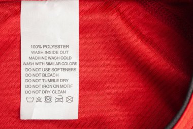 Kırmızı formalı polyester spor tişörtte beyaz çamaşır yıkama talimatları etiketi