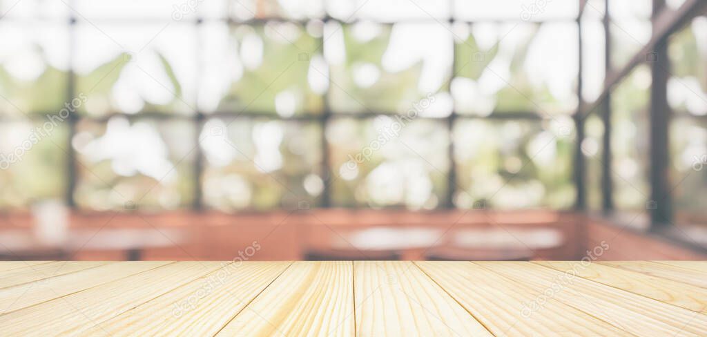 Empty wooden table top with cafe restaurant coffee shop window interior abstract blur defocused with bokeh light background for montage product display