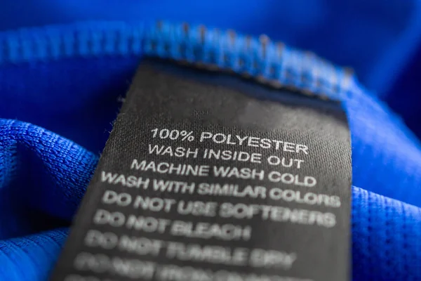 蓝色涤纶运动衫上的黑色洗衣服洗涤说明服装标签 — 图库照片