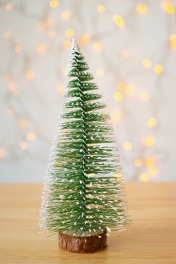 Ahşap masanın üzerinde Bokeh ışıklandırmalı bir Noel ağacı var.
