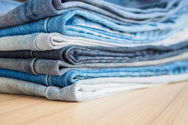 Ahşap arka planda kot pantolon yığını