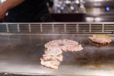Japon şef Teppanyaki restoranında et pişiriyor.