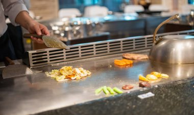 Japon şef Teppanyaki restoranında et pişiriyor.