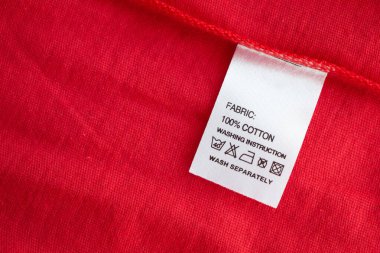 Beyaz çamaşır yıkama talimatları kırmızı pamuklu gömlekte etiket