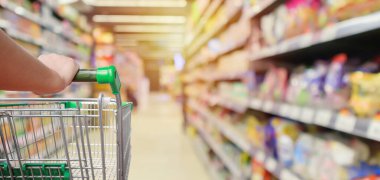 Süpermarket koridorundaki alışveriş arabasının içinde ürün rafları iç odaklanmış bulanık arkaplan