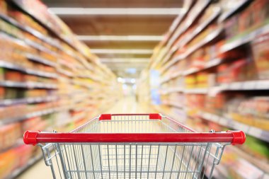 Market koridoru ve içi ürün raflarıyla dolu boş kırmızı alışveriş arabası soyut bulanık arkaplan
