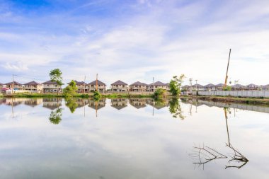 Yeni ev binası yansıması gölde suyla birlikte bulutlu ve mavi gökyüzü olan konut inşaat sahasında.