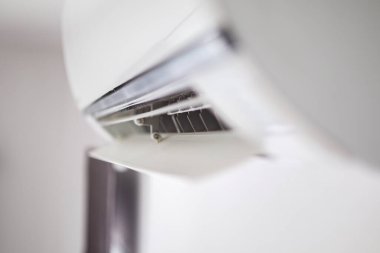 Beyaz duvar odasının arka planında klima var.