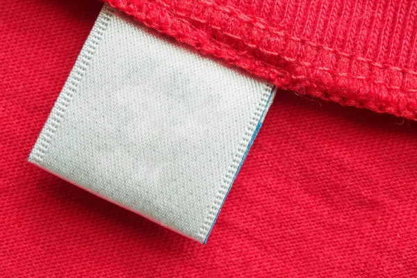 Cucian Putih Kosong Label Pakaian Pada Warna Merah Katun Kemeja — Stok Foto