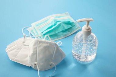 Alkol dezenfektanı jeli el yıkama şişesi. Mavi arka planda N95 tıbbi maske. Coronavirüs önleme kavramı.