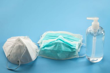 Alkol dezenfektanı jeli el yıkama şişesi. Mavi arka planda N95 tıbbi maske. Coronavirüs önleme kavramı.