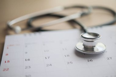 Ahşap masa arkası doktor randevu konseptinde takvim tarihli steteskop