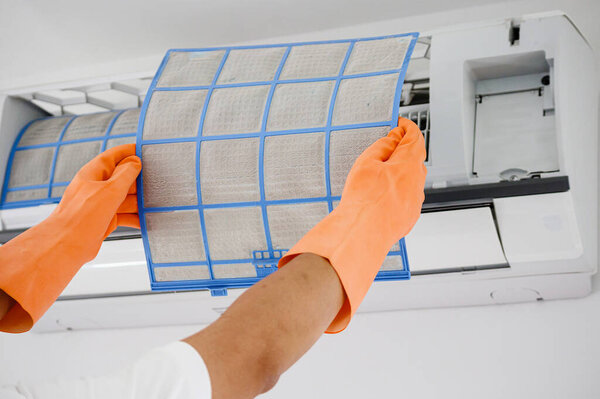 Asian man cleaning air conditioner dirty filter