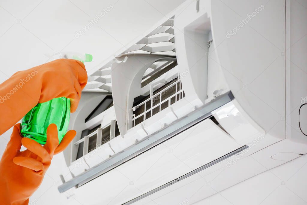 Asian man cleaning air conditioner with spray bottle