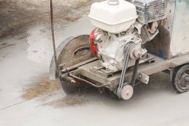 İnşaat alanında beton yol kesen elmas testeresi kullanan bir işçi.