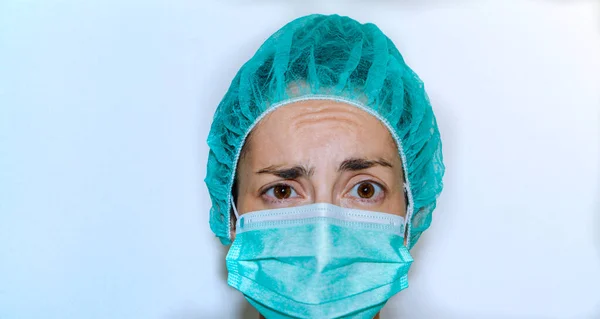 Koruyucu teçhizatlı hemşire şaşırdı. Maske ve yeşil şapka
