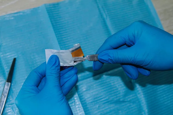 Mavi eldivenli el yeni bir bıçakla neşter tutuyor.