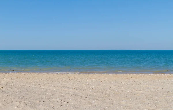 Gökyüzü, deniz, kum ve güneşli sahilde kimse yok. Tatil ve rahatlama. Turizm