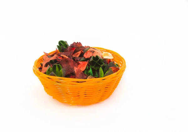 Beyaz arka planda yeşil ve kırmızı çiçekli turuncu sepet. Dekorasyon ve gevşetici nesne 