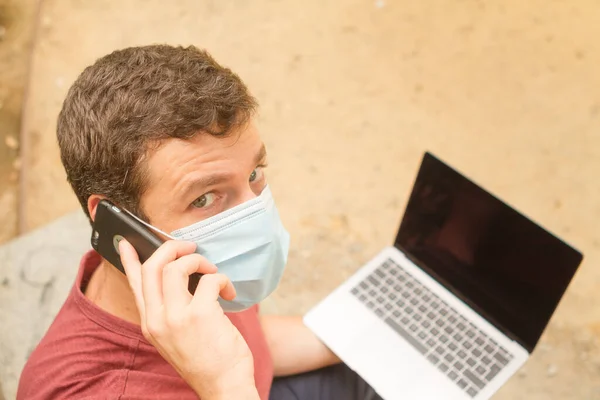 Bilgisayarlı ve maskeli uzaktan kumandalı bir adam..