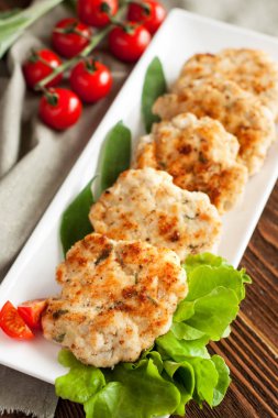 Ev yapımı tavuk köftesi ile sarımsak ve adaçayı, marul salata ve domates ile servis edilir