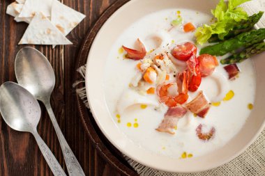 Deniz mahsulleri çorbası kalamar, karides, pastırma, sebze ve ahşap masa üzerinde kuşkonmaz ile