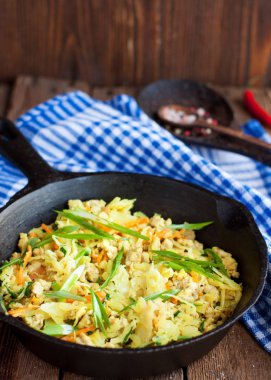 Domuz eti, havuç, soğan ve zerdeçal rustik ahşap masa üzerinde siyah tavada haşlanmış lahana