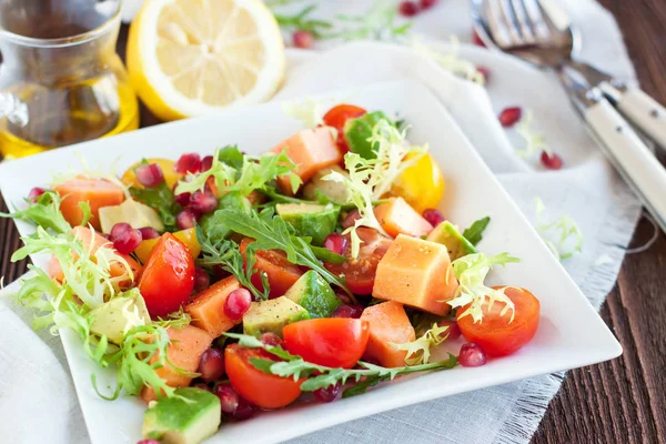 Ripe papaya and avocado salad with cherry tomatoes and pomegranate seeds. Healthy lunch