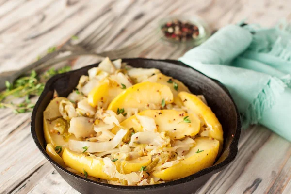 Light sauteed cabbage with apples, mustard and fresh thyme leaves in cast iron frying pan