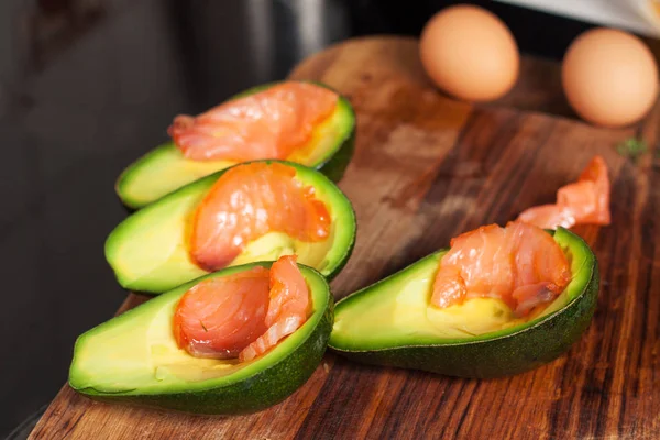 Preparation of baked eggs in avocado with smoked salmon. Ingredients and cooked meal also in portfolio