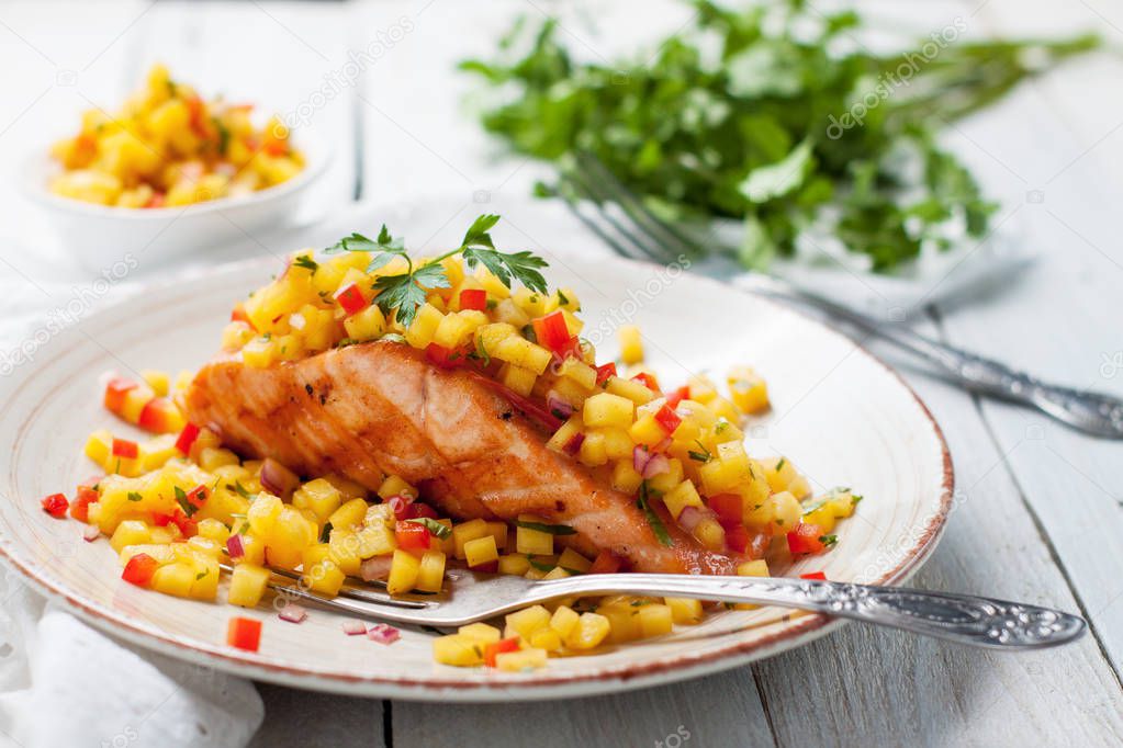 Grilled salmon fillet with mango salsa on white wooden table. Healthy eating