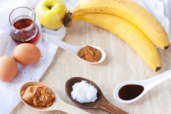 Taze elma, muz, yumurta, badem ezmesi, tarçın, akçaağaç şurubu, mermer yüzey üzerinde vanilya ekstresi. Paleo elma tarçın krep için malzemeler