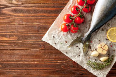 Ahşap arka plan, metin için yer ile domates, limon, sarımsak ve baharat ile taze orkinos takip