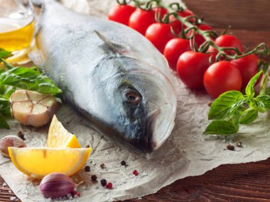 Taze ton balığı kiraz domates ve otlar ile kağıt ahşap doku üzerinde yatarken