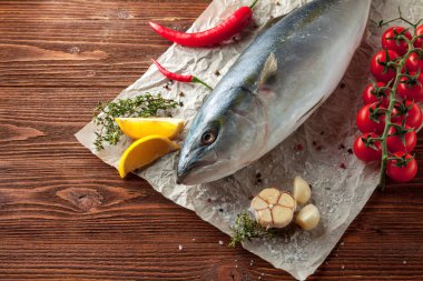 Taze ton balığı kiraz domates ve otlar ile kağıt ahşap doku üzerinde yatarken