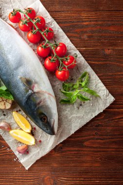 Taze ton balığı kiraz domates ve otlar ile kağıt ahşap doku üzerinde yatarken