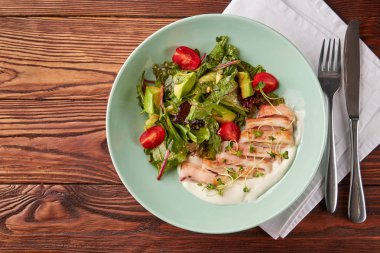 Sağlıklı sebze salatası ve ahşap masa üzerinde krema sos ile kase tavada kızartılmış kalamar halkaları