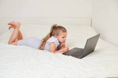 Laptop çizgi film izlerken evde, yatakta yatarken şirin küçük kız