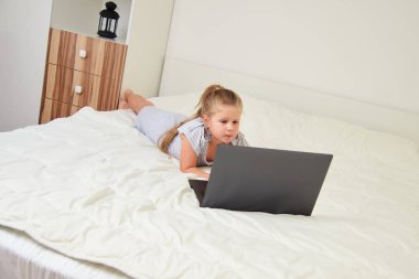 Küçük sarışın kız yatak odasında yatarken laptop arıyorum