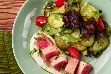 Nadir kurutulmuş tuna dilimleri ahşap masa üzerinde kase taze sebze salatası ile