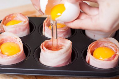 Lezzetli domuz pastırması yumurta muffins pişirme. CUPS ile ekmek ve domates dilim pastırma üzerinden dökülen çiğ tavuk yumurta